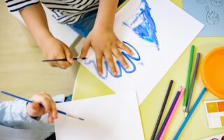 An image of a child tracing their hand on a piece of paper with blue paint