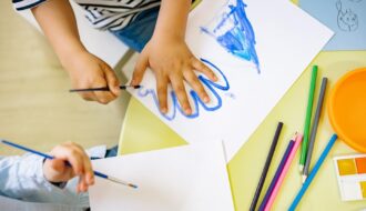 An image of a child tracing their hand on a piece of paper with blue paint